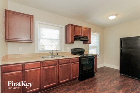 A kitchen with wooden cabinets and a black refrigerator.