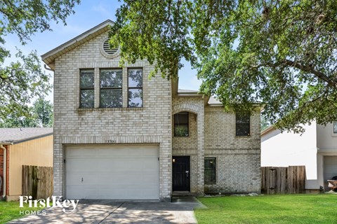 A brick house with a white garage door is for sale.
