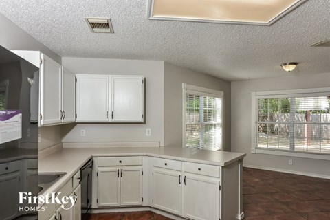A kitchen with white cabinets and a tile floor.
