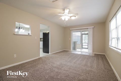 a spacious living room with carpet and a ceiling fan
