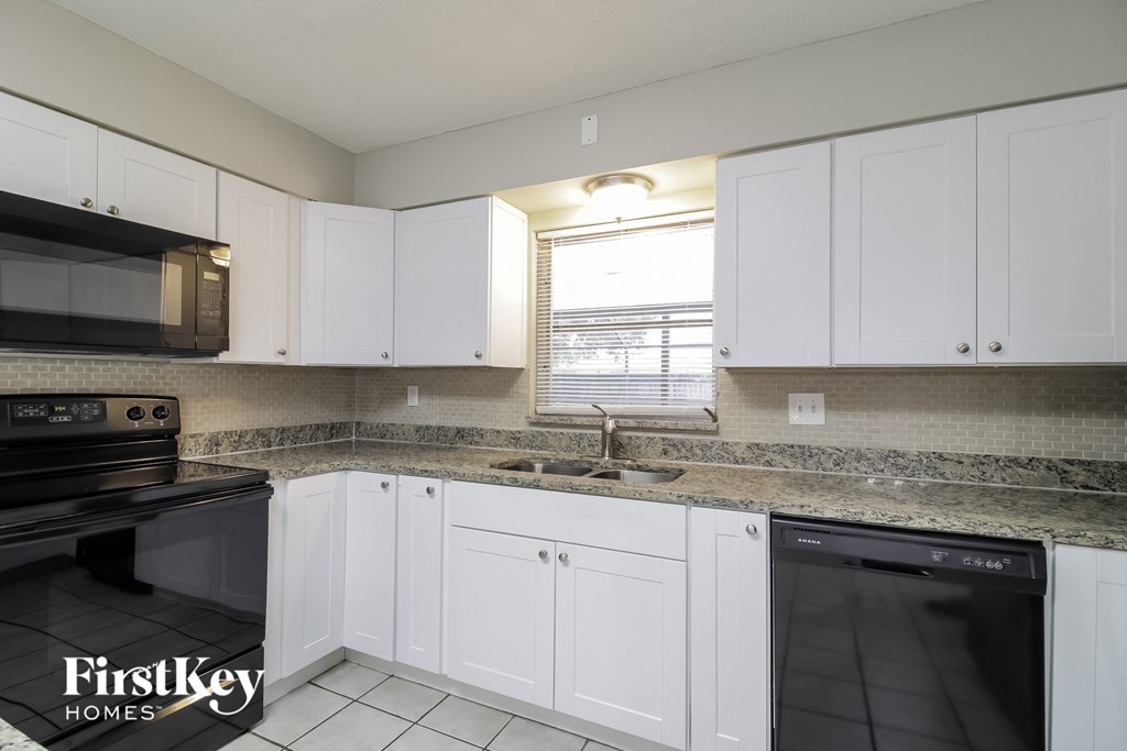 a kitchen with white cabinets and granite counter tops and black appliances