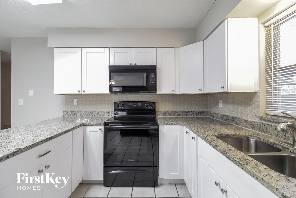 a kitchen with white cabinets and black appliances and granite counter tops