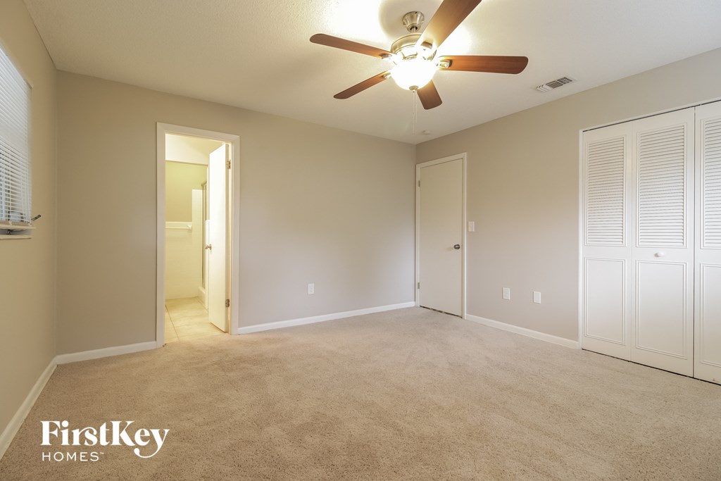an empty living room with a ceiling fan and a closet