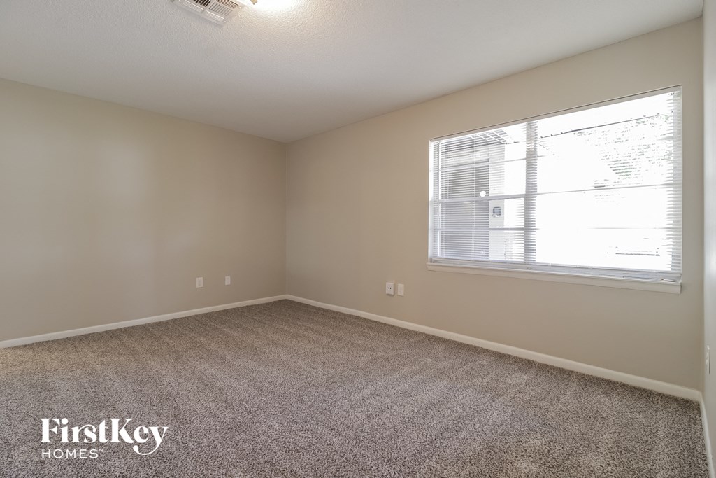 a bedroom with carpet and a large window