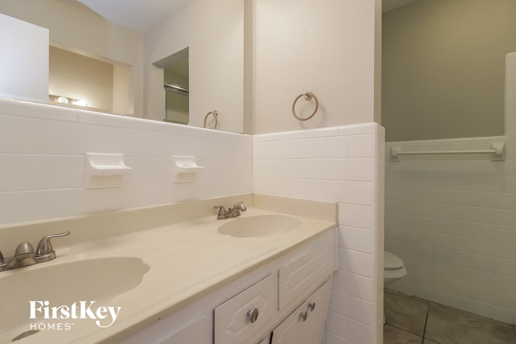 a white bathroom with two sinks and a toilet