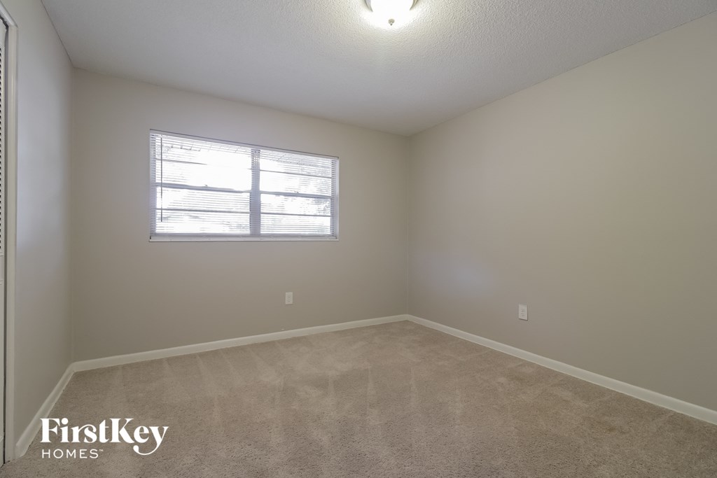 a bedroom with a window and a carpeted floor
