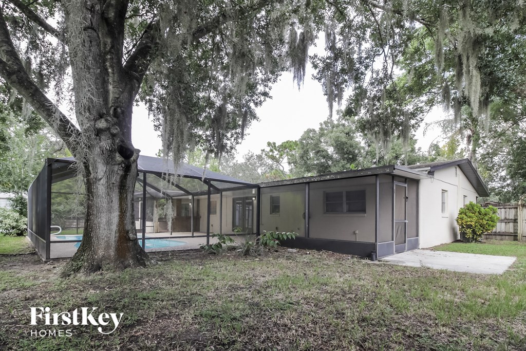 the exterior of a house with a large tree and a pool