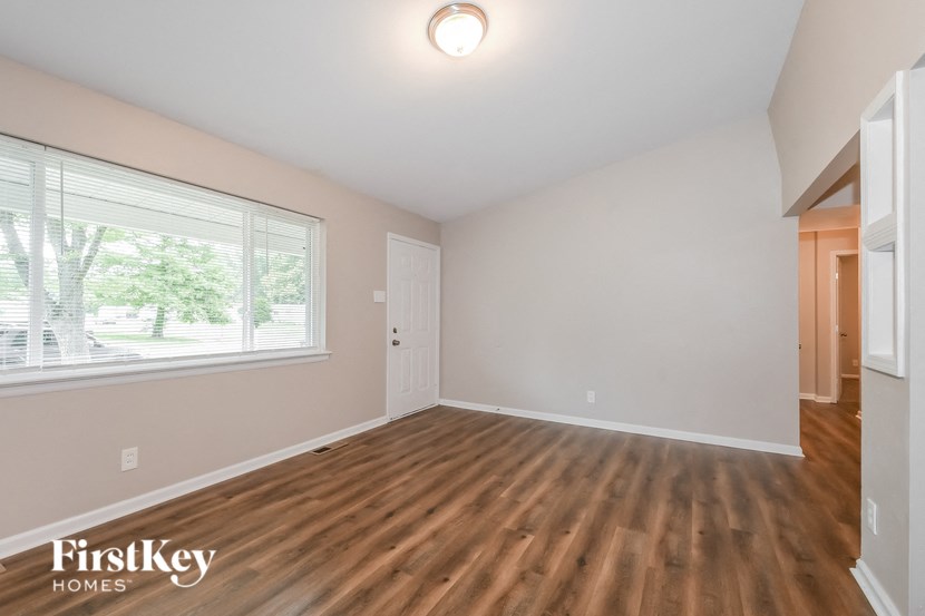 A room with wooden flooring and a window with blinds.