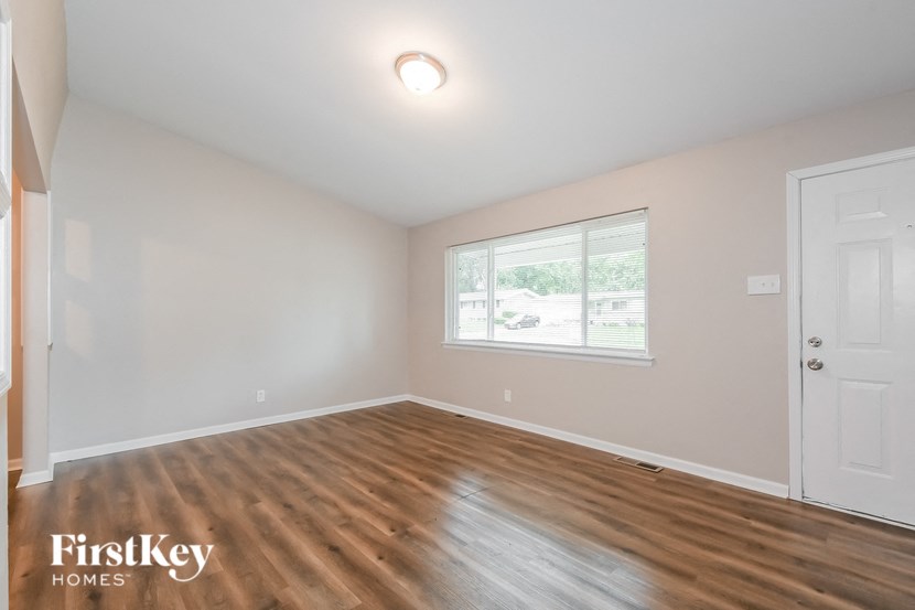 A room with wooden flooring and a window showing a view of a street.