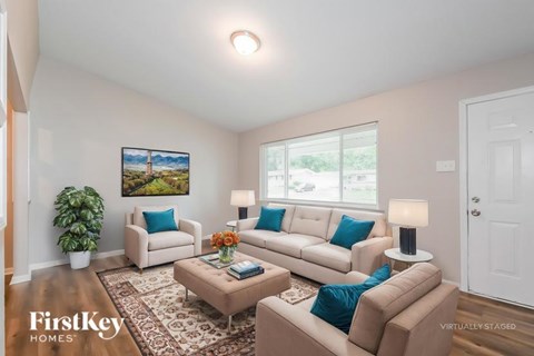 A living room with a couch, chair, and a painting on the wall.