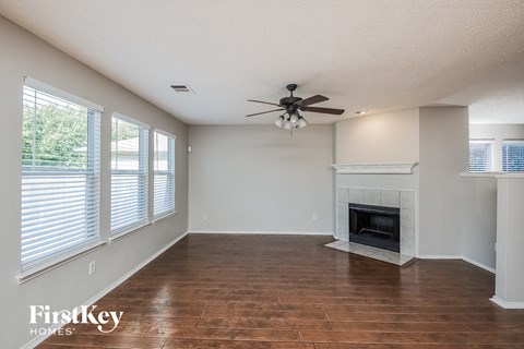 A spacious living room with a fireplace and a ceiling fan.