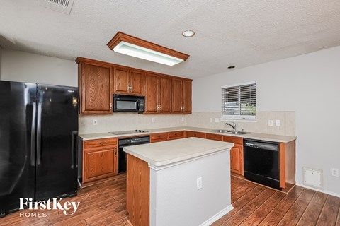 A kitchen with wooden cabinets and a black refrigerator.