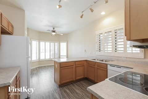 an empty kitchen with wood flooring and white walls and wooden cabinets