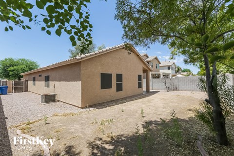 a house with a dirt yard and trees in front of it