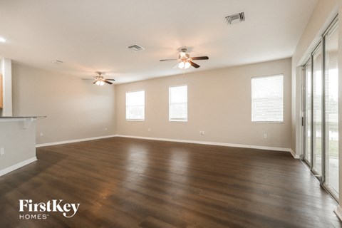 A spacious room with wooden flooring and a ceiling fan.