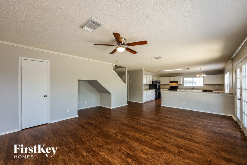 A spacious room with wooden floors and a ceiling fan.