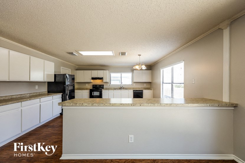 A kitchen with a granite countertop and a black refrigerator.