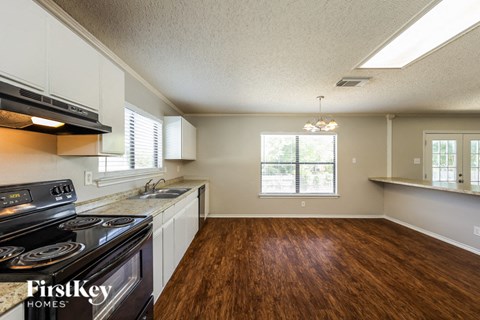 A kitchen with a stove top oven and a wooden floor.