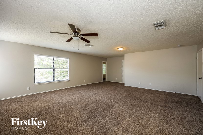 A spacious room with a ceiling fan and carpeted floor.