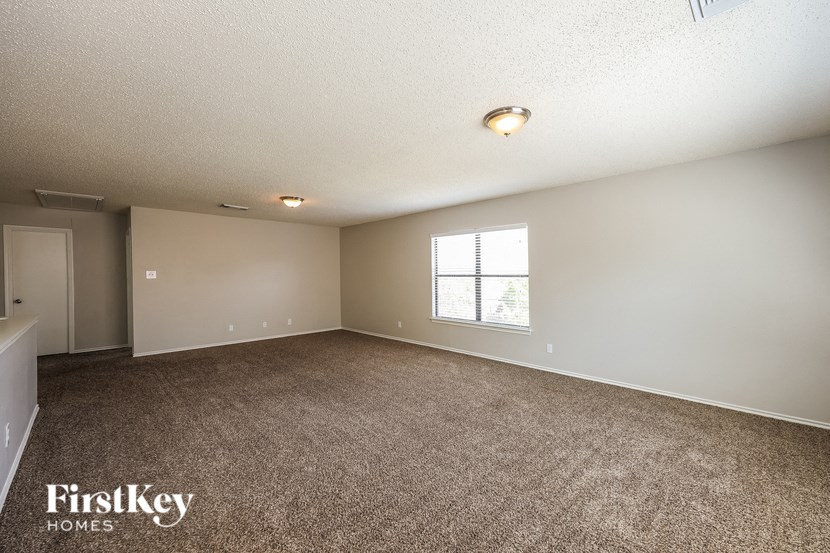 A room with a carpeted floor and a window with blinds.