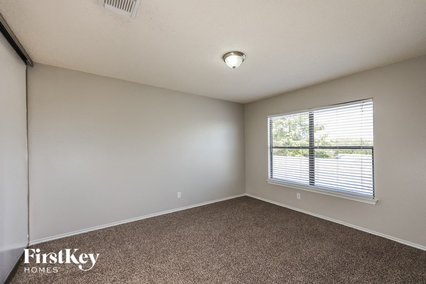 A room with a carpeted floor and a window with blinds.