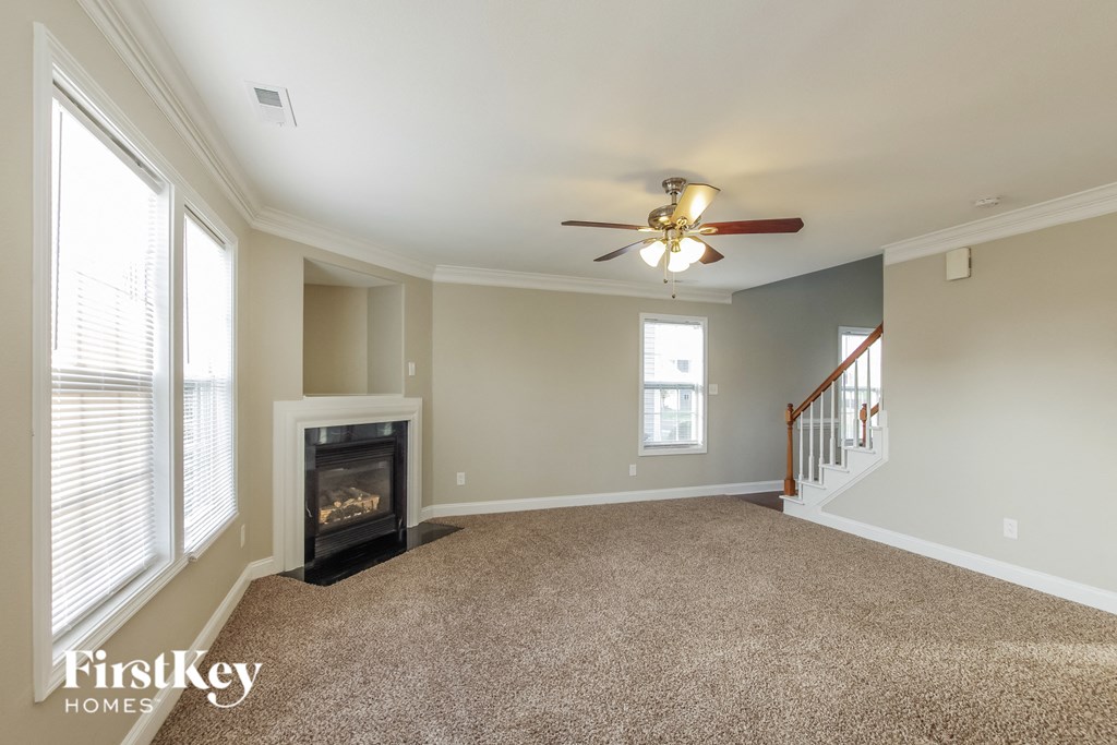 an empty living room with a fireplace and a ceiling fan