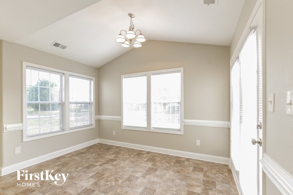 an empty dining room with windows and a chandelier