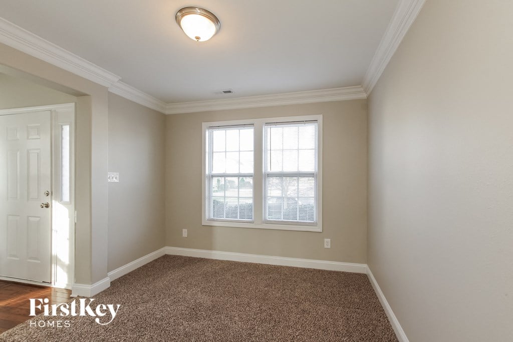 a empty dining room with a carpeted floor and two windows