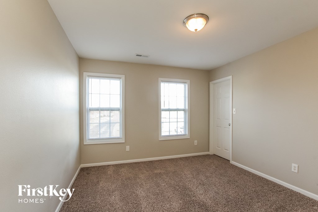an empty room with two windows and a door