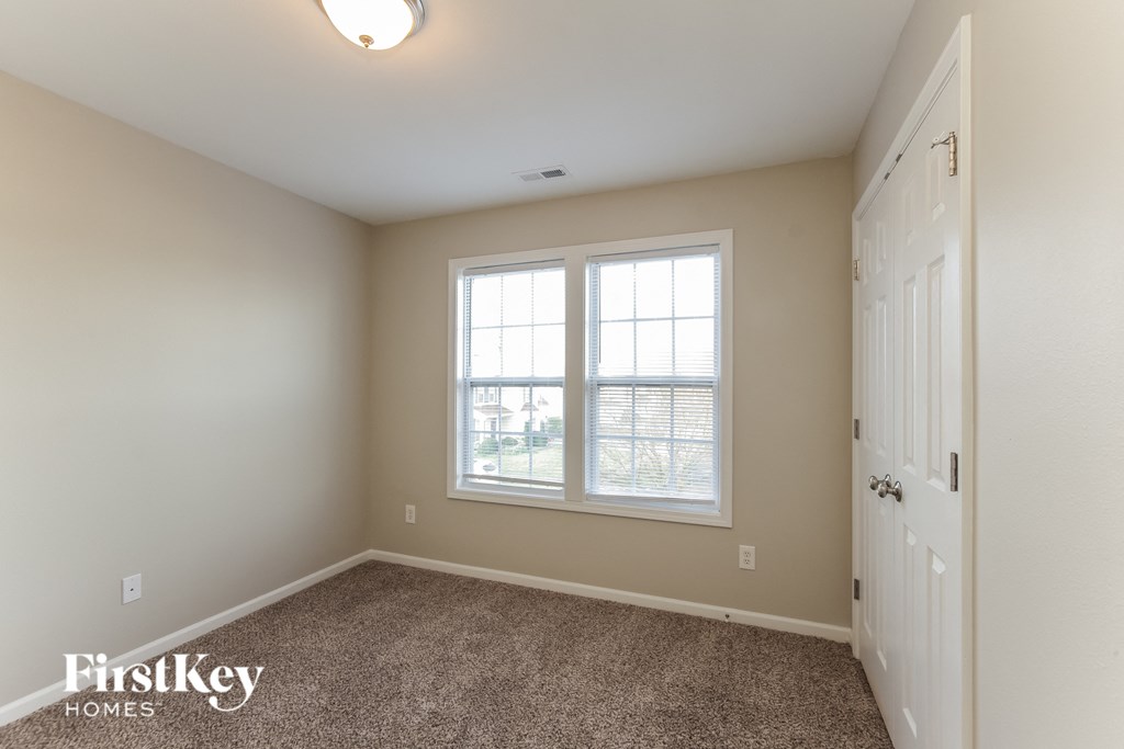 a bedroom with a carpeted floor and two windows and a white door