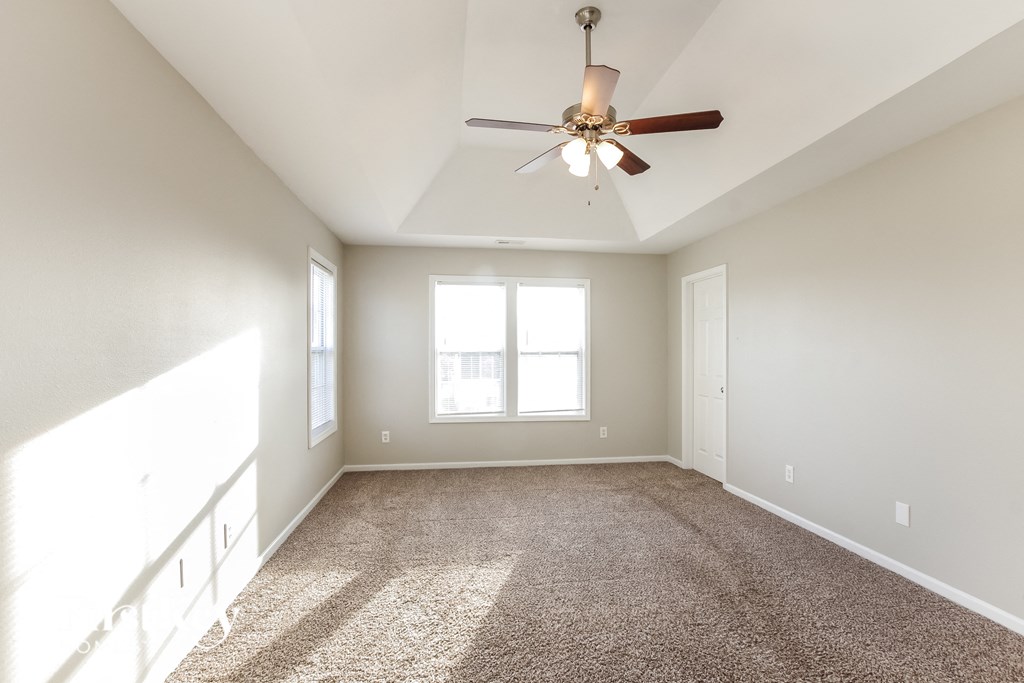 an empty living room with a ceiling fan and a window