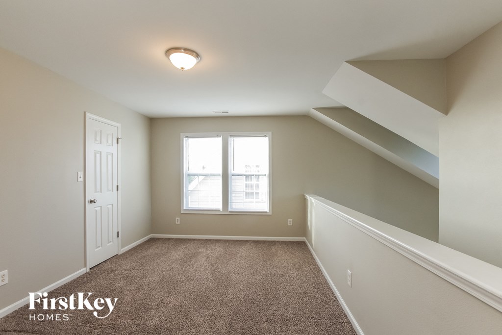 a bedroom with stairs and a white door and a window