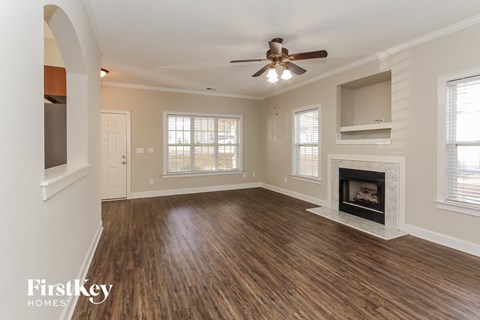 an empty living room with a fireplace and a ceiling fan