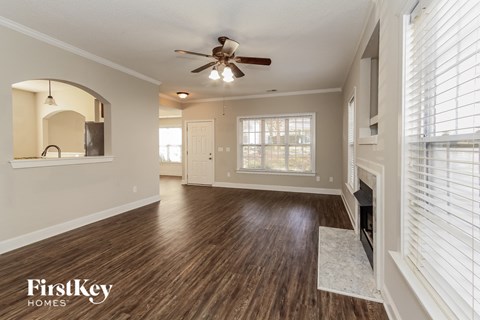 an empty living room with a ceiling fan and a fireplace
