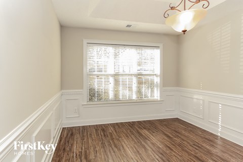 a dining room with white walls and wood flooring and a window
