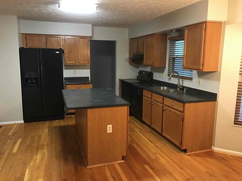 A kitchen with black appliances and wooden cabinets.