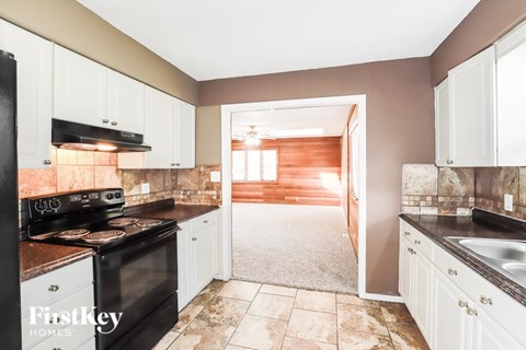 A kitchen with a black stove top oven and white cabinets.