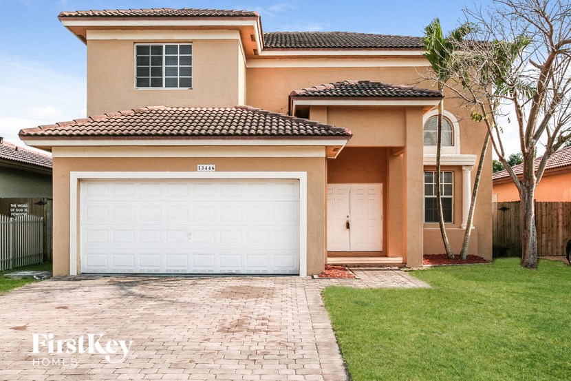 A house with a white garage door and a brick driveway.