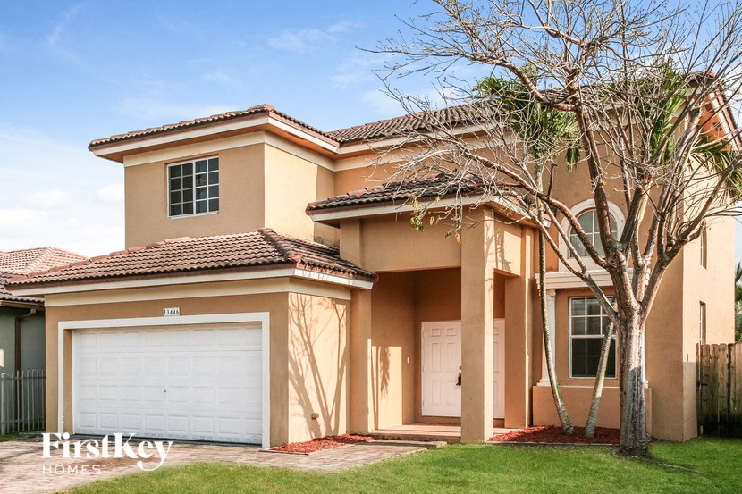 A house with a garage and a tree in front of it.