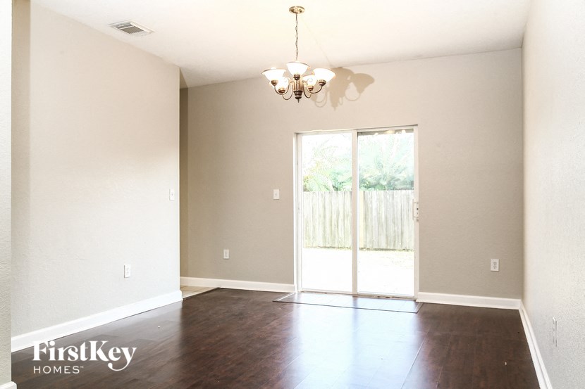 A room with a chandelier and sliding glass doors.