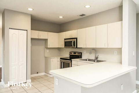 A kitchen with white cabinets and appliances.