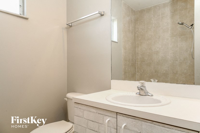 A bathroom with a toilet, sink, and mirror.