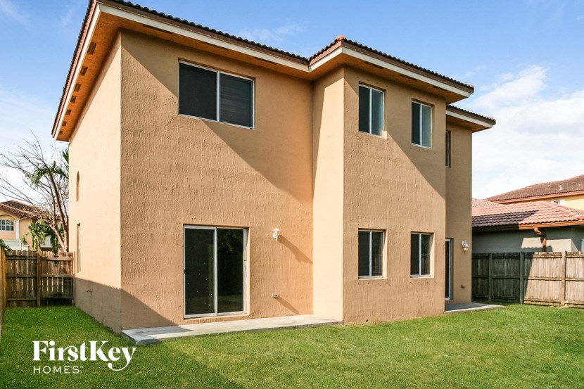 A tan stucco house with a brown roof and a white window.