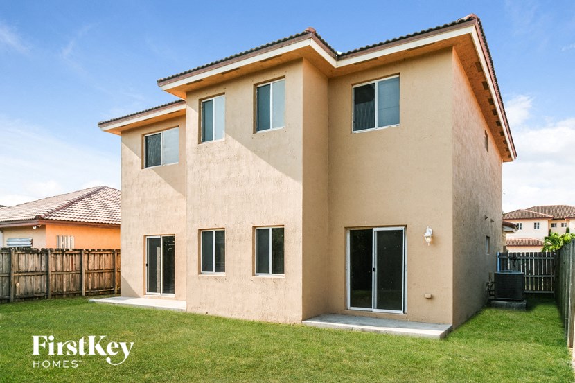 A beige house with a black door and windows.