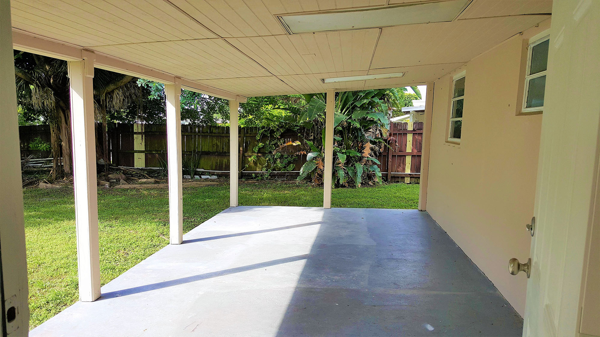 a covered porch with a view of the yard and grass