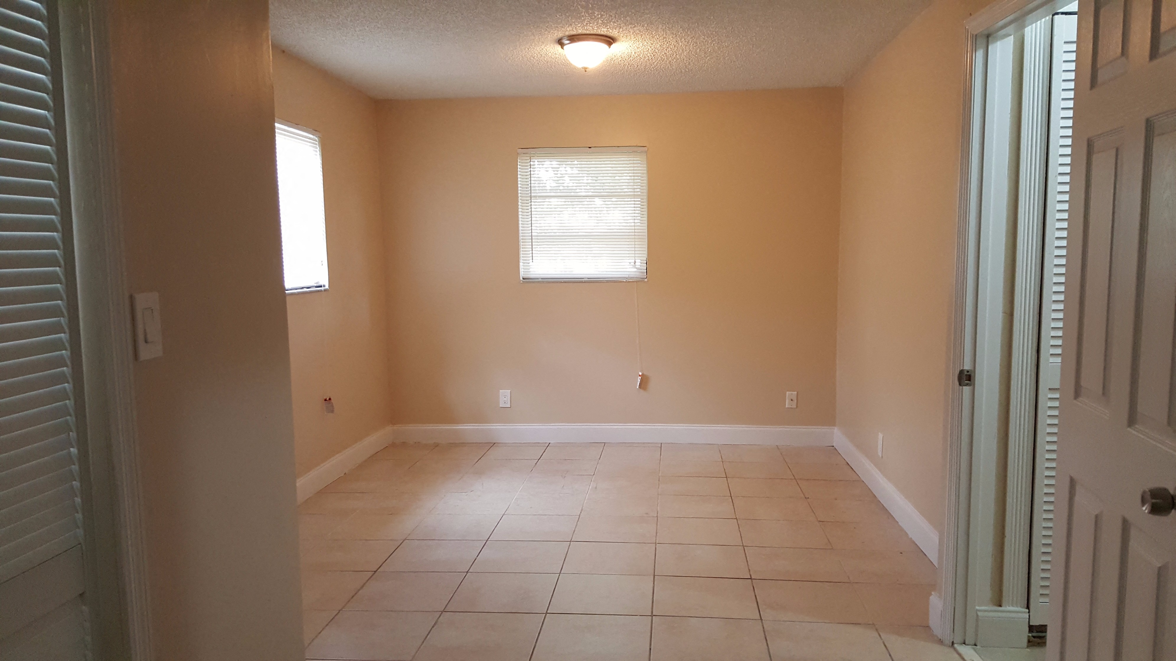 an empty living room with a tile floor and a window