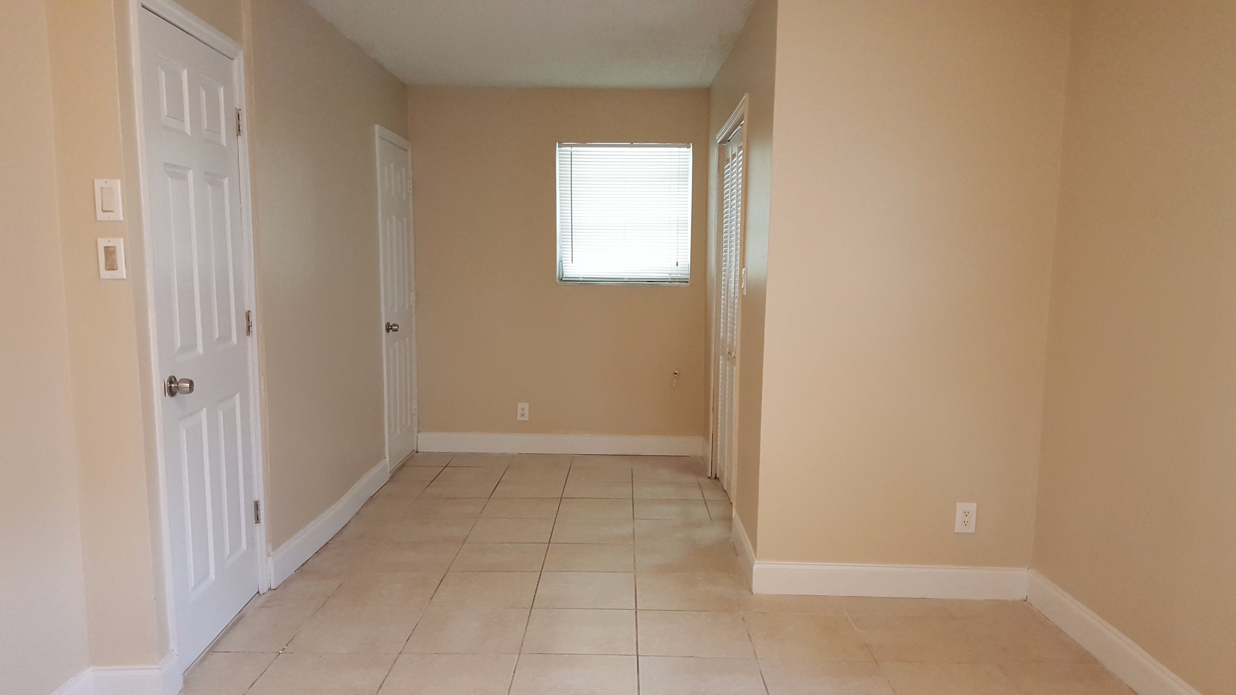 a hallway with a door and a window and a tiled floor