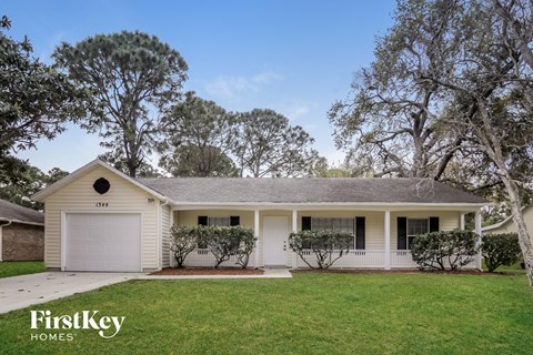 a white house with a lawn and trees