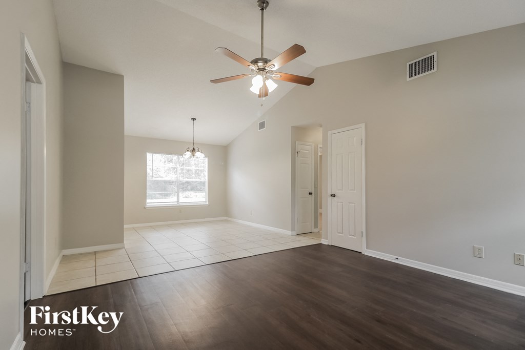 an empty living room with wood floors and a ceiling fan