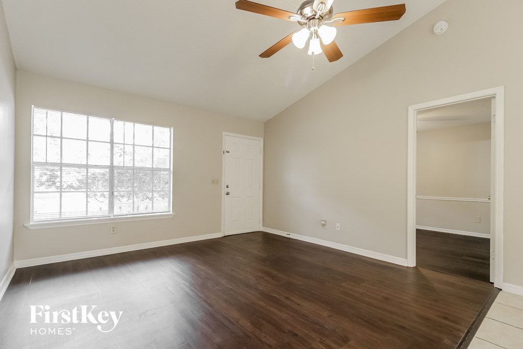 an empty living room with a ceiling fan and a window